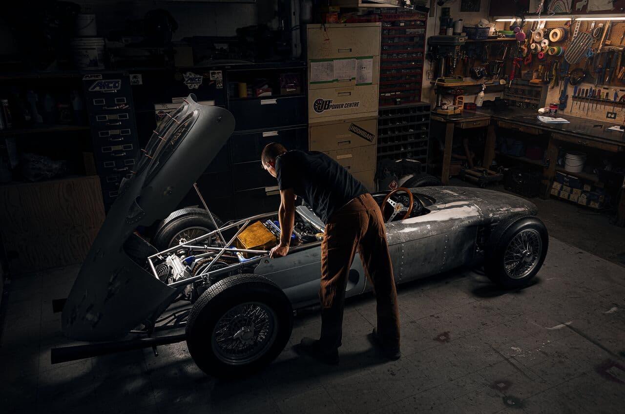 A mechanic working on a classic racing car in a workshop