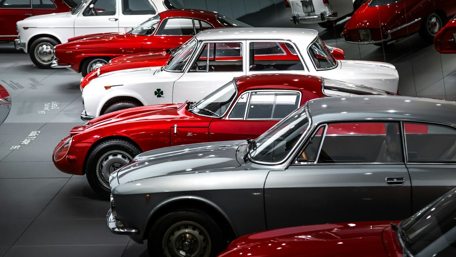 Rows of 1960s classic coupés and saloons parked closely together indoors
